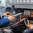 A technician holding a digital tablet next to an electric truck.