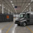 A Workhorse battery-electric step van parked beside a branded mobile AI data center unit inside a warehouse.